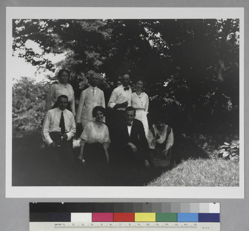 Group portrait of four women and four men, including Edwin Powell Hubble, posed in the shade of a tree, approximately 1914