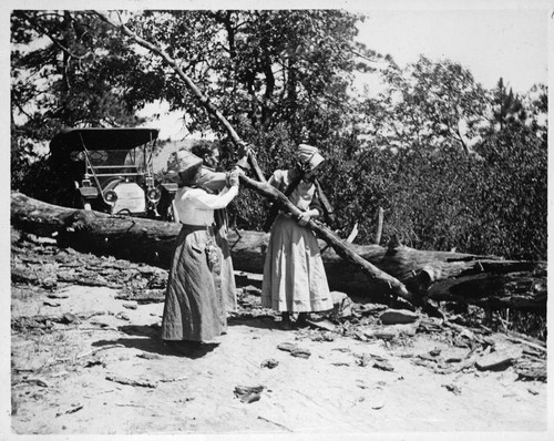 Grace Nicholson and others pushing log off road so automobile can pass