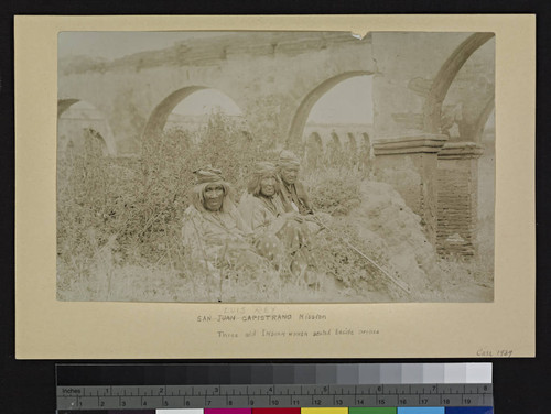 San Luis Rey Mission. Three old Indian women seated beside arches