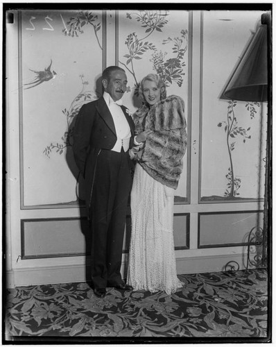 Adolphe Menjou and woman in evening gown