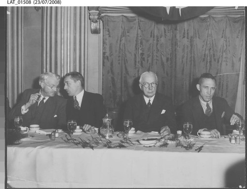 Harry Chandler converses at dining table with cigar in hand