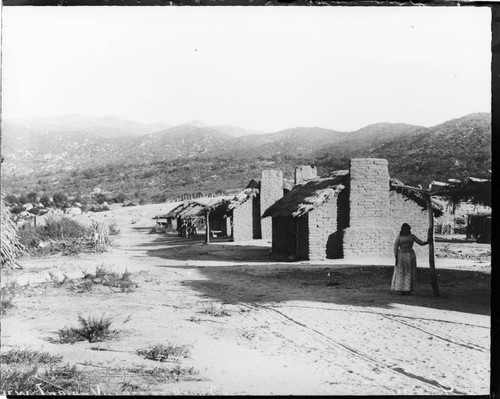 Desert landscape with adobe houses on dirt road