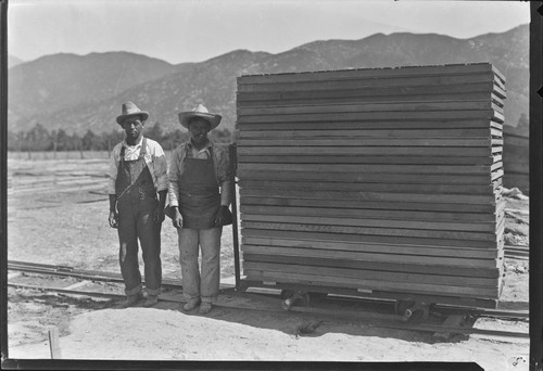 Two workers next to drying racks