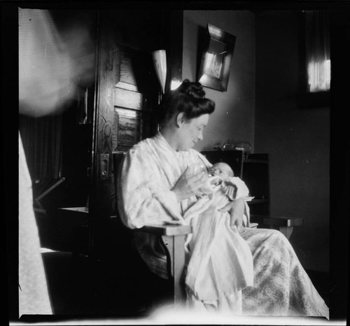 Woman holding baby, sitting in chair