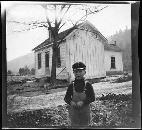 Little boy and dog in front of a small house