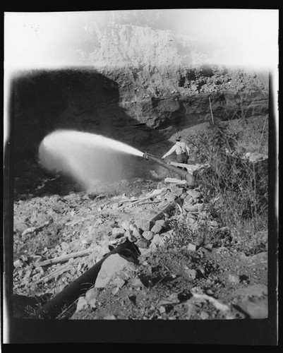 Unidentified scene showing man with a pipe releasing water into a canyon