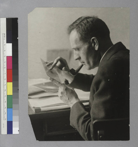 Edwin Powell Hubble looking through a magnifying loupe at a photographic glass plate