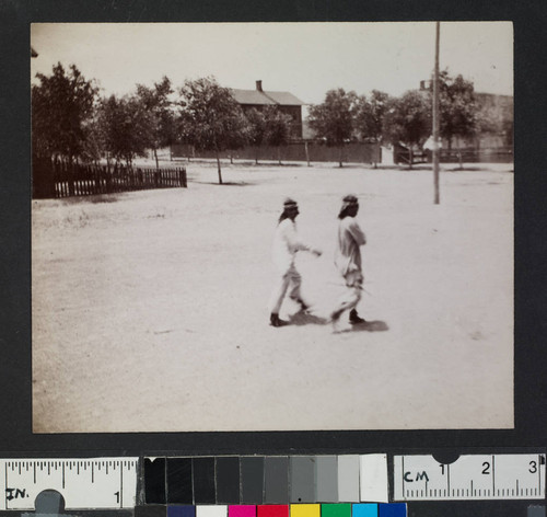 Two Pueblo Indian men walking through a town