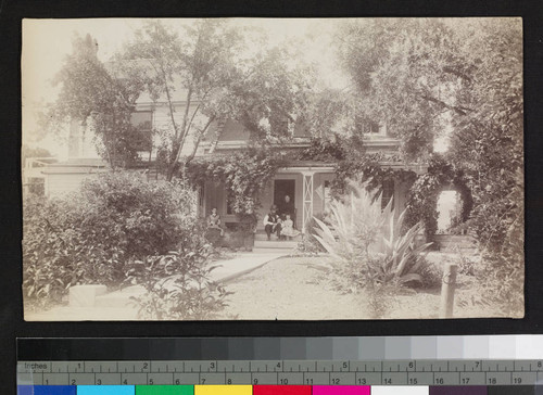 View of people sitting on the porch of a house, with garden