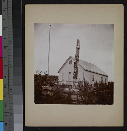 Totem pole and flag pole in front of a house, Fort Wrangell, Alaska