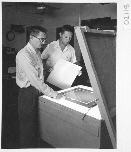 James McClanahan and Hendrik Rubingh standing at a contact printer for sky survey atlas prints