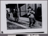 W. Parker Jr. owner of Lyon Pony Express Museum at Arcadia, Calif., helps his father carry the longest shotgun in the world from Museum Gun Room