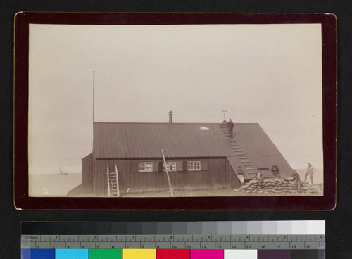 Six unidentified men on top of and beside house