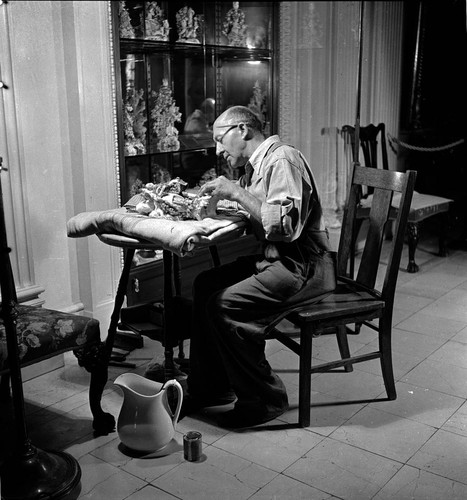 Attendant cleaning or repairing Chelsea porcelain in the Huntington residence
