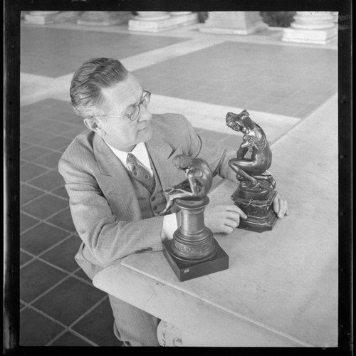 Maurice Block examining figurines