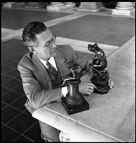Maurice Block examining two small bronzes