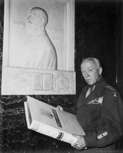 General George S. Patton with an oversized copy of Mein Kampf under a plaque of Henry E. Huntington, June 11, 1945