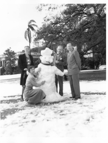 Huntington employees stand around a snowman, January 11, 1949