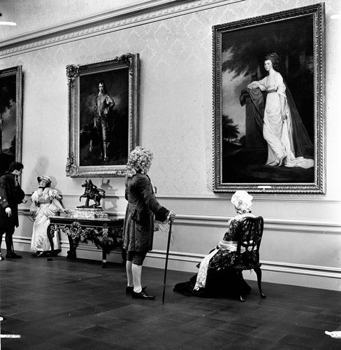 Four people in period costume in the portrait gallery in the Huntington residence