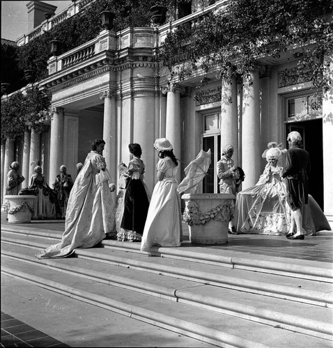 Twelve people in period costume on the terrace steps by the south entrance of the Huntington residence