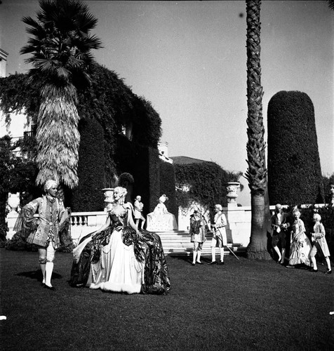 Nine people in period costume on the lawn by the south terrace of the Huntington residence, looking east