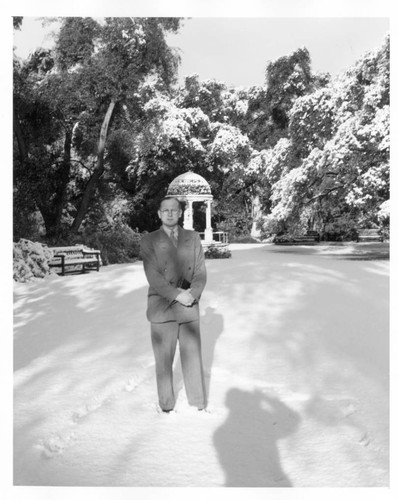 Irwin Morrkisch stands in front of a statue after snowfall, January 11, 1949