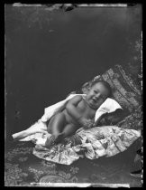 Portrait of a nude infant lying on a cushion