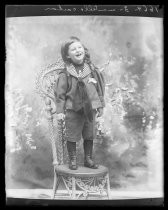 Portrait of a child in sailor suit standing on wicker chair