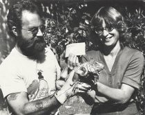 Man and woman holding an iguana