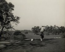 Golfer taking a swing, in plus-fours