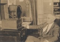 Lee de Forest sitting at a desk with radio receiver