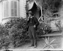 Man in suit and hat, with pocket watch, outside house, c. 1912