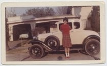 Young person standing in front of white two door coupe