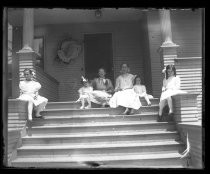 Group of girls seated on steps of Victorian house