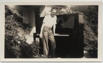 Bohnett family member standing with hand on piano outside