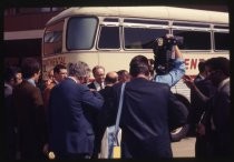 Television crew and crowd in front of bus