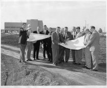 Group of men looking at large plans at construction site