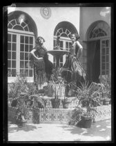 Two women posing on fountain in Fiesta de las Rosas costume