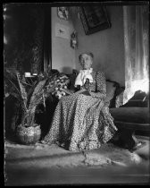 Older woman seated on sofa, reading