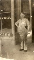 Man in apron in front of Maxwell's Bicycles