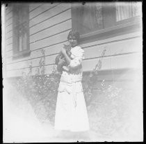 Young woman posing along side of house, holding a cat