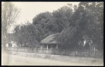 Ranch house surrounded by picket fence, circa 1918