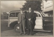 Two men in suits standing in front of station wagon