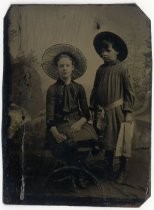 Portrait of two children in dresses and hats, with parasol