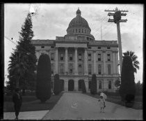 Child in dress, bonnet and parasol in front of domed building