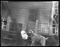 Young child with goat, outside a house