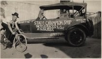 Cyclist and truck advertising the State Championship Bicycle Races