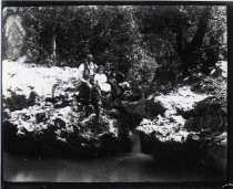 Man posing with children next to waterfall