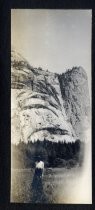 Woman posing in field with tall cliffs behind her