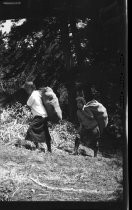 Two people hiking up a hill with large sacks